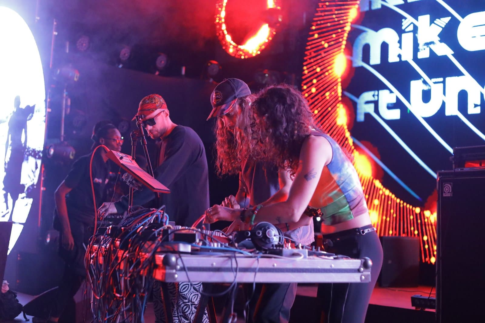 Performers using electronic music equipment on a brightly lit stage in a Nyege Nyege promotional photograph.