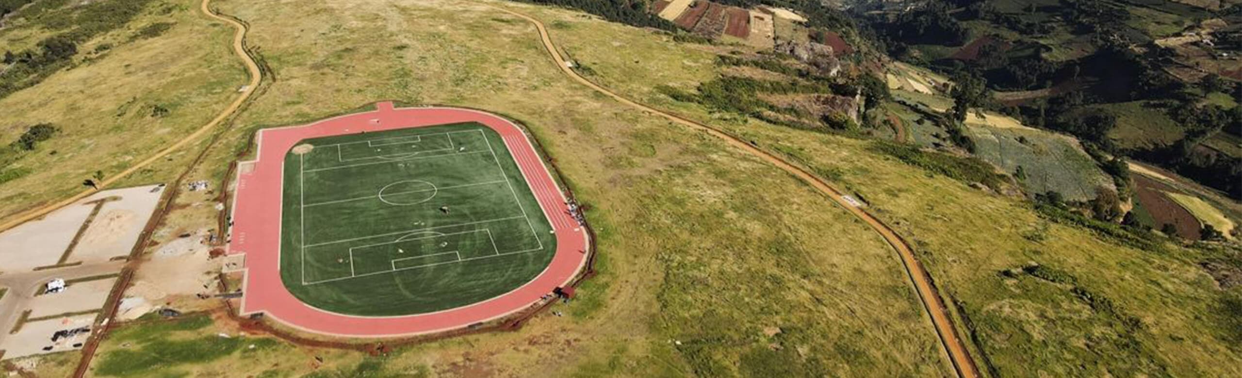 The running track and pitch at Teryet, surrounded by green hills.