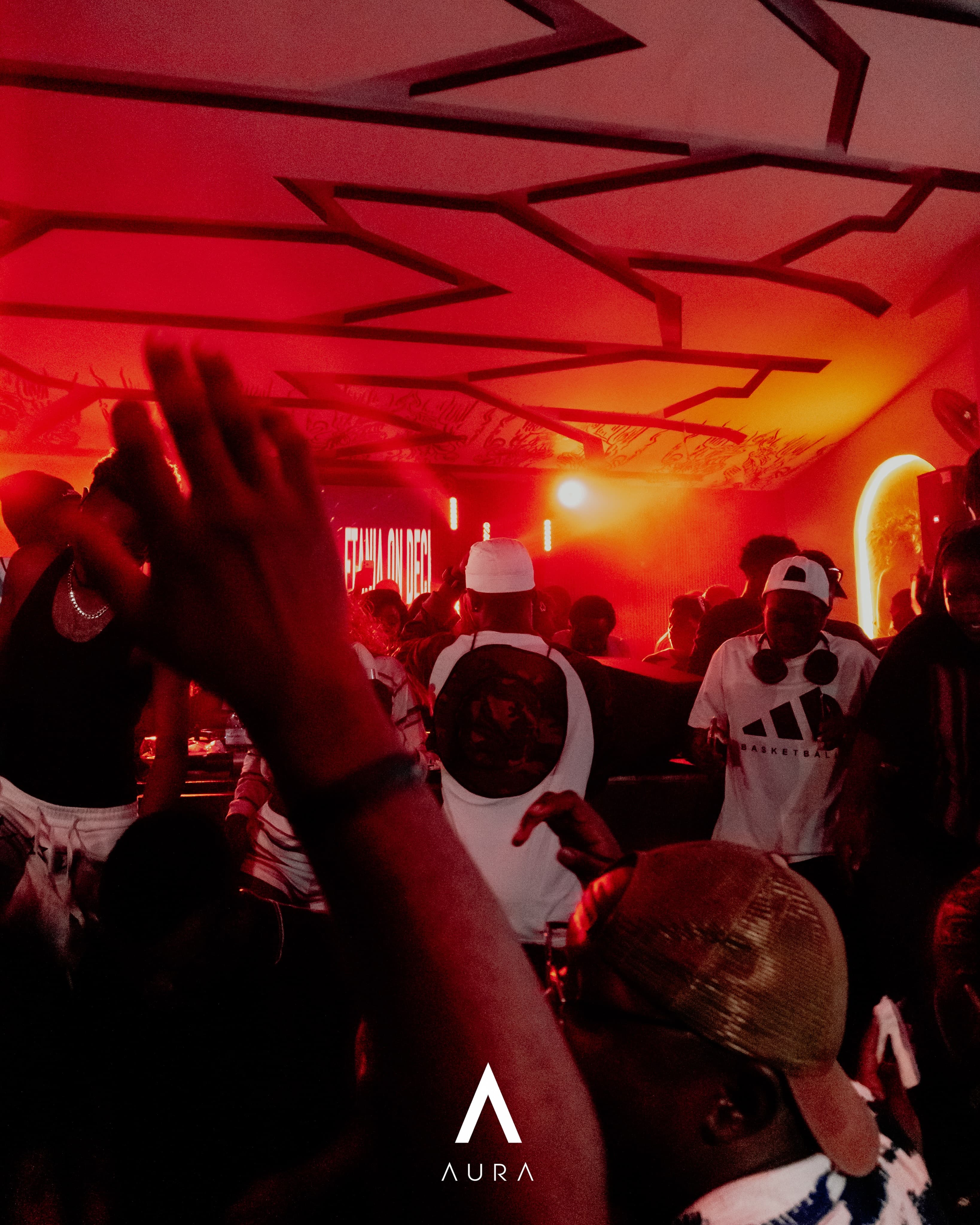 Music and a crowd inside Aura Lounge under red lighting.