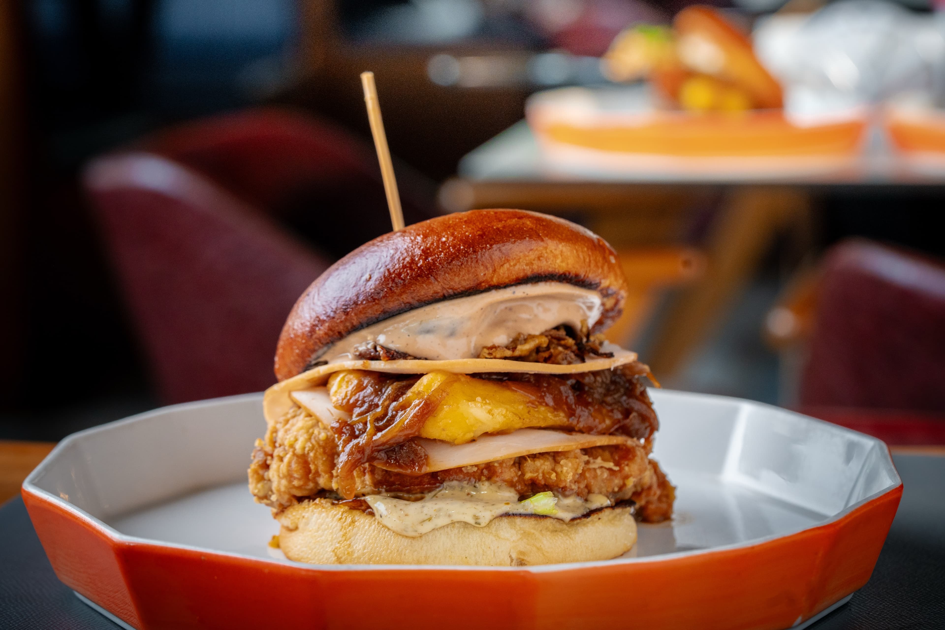 Burger served on a white and orange plate in Dstrkt24 venue food photography.