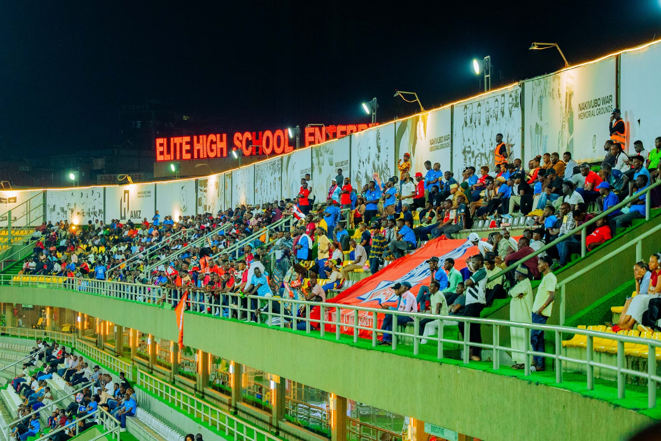Fans in the stands at Hamz Stadium, with the Nakivubo War Memorial Grounds name visible.